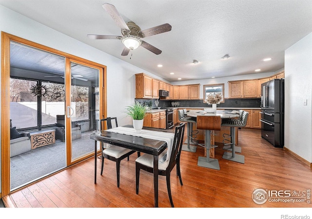 dining area with ceiling fan, hardwood / wood-style floors, and a textured ceiling