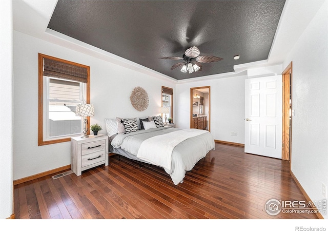 bedroom with dark wood-type flooring, ceiling fan, a raised ceiling, and a textured ceiling