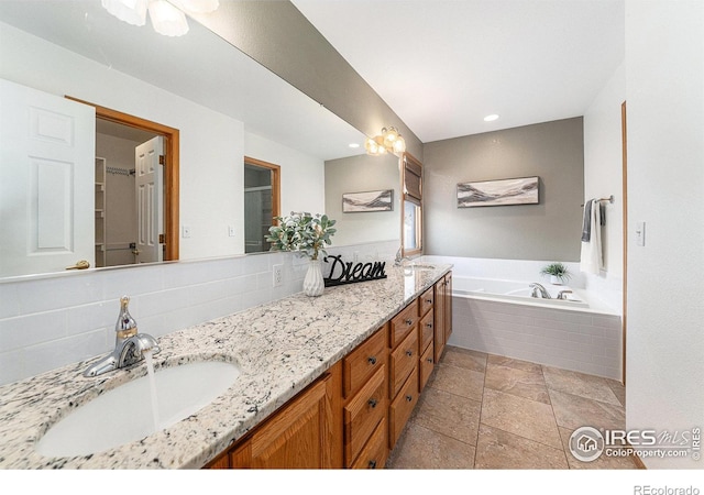 bathroom with tasteful backsplash, vanity, and tiled tub