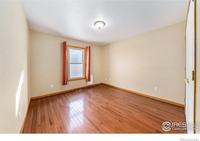 unfurnished room with radiator heating unit and wood-type flooring