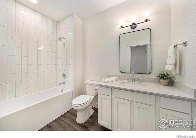 full bathroom with vanity, hardwood / wood-style floors, toilet, and tiled shower / bath