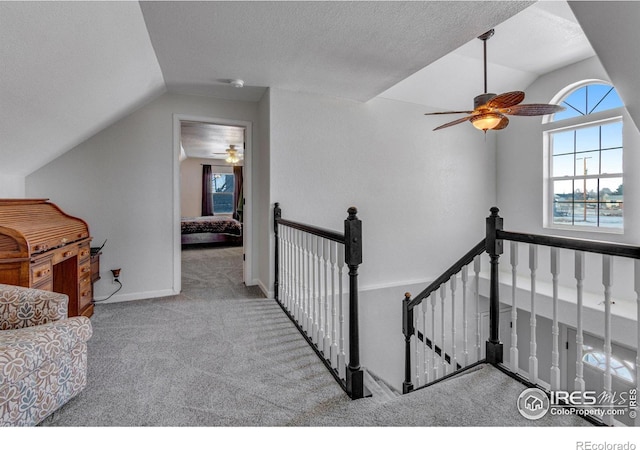 interior space with lofted ceiling, a textured ceiling, carpet, and an upstairs landing