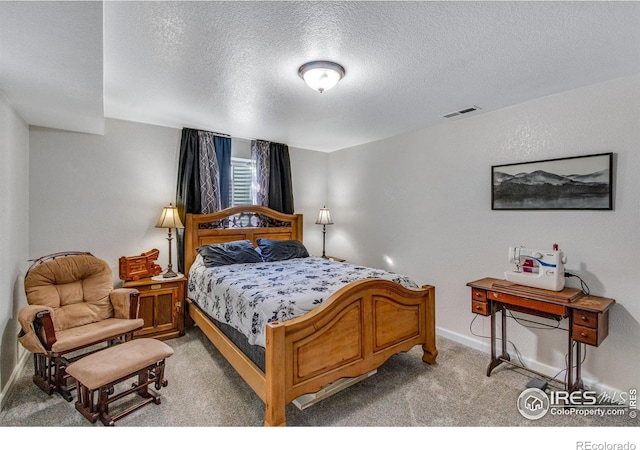 bedroom with baseboards, visible vents, light carpet, and a textured ceiling