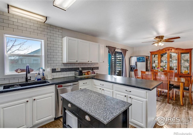 kitchen featuring a peninsula, a sink, white cabinetry, appliances with stainless steel finishes, and tasteful backsplash