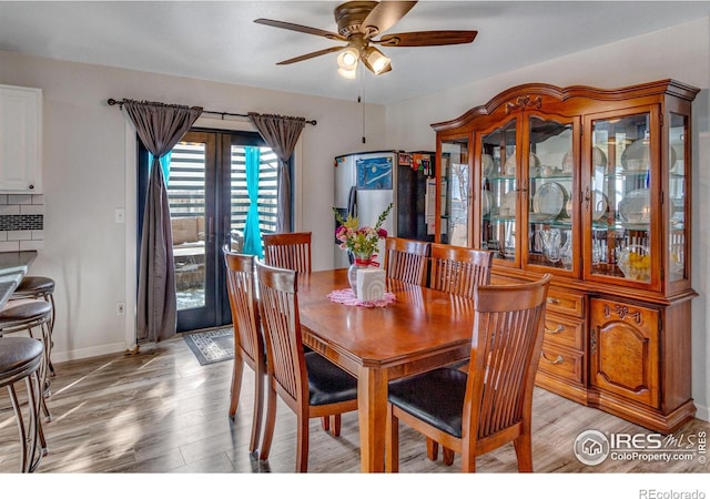 dining space with light wood finished floors, a ceiling fan, and baseboards