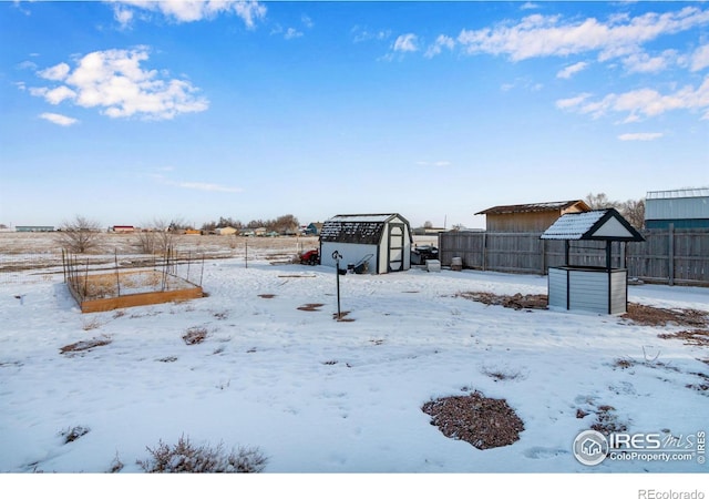 yard layered in snow with an outbuilding, fence, and a storage shed