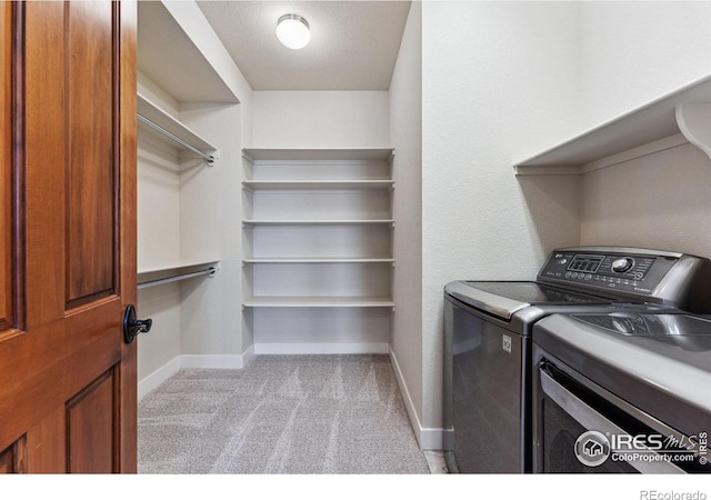 washroom featuring washing machine and clothes dryer and light colored carpet