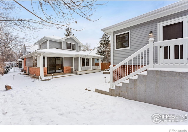 snow covered back of property with a porch