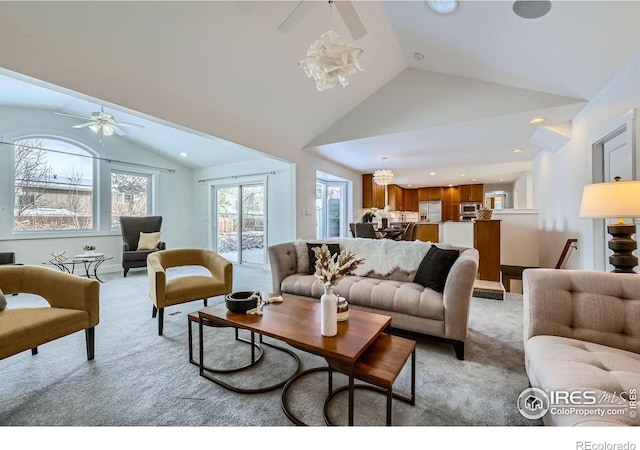 carpeted living room with a wealth of natural light, vaulted ceiling, and ceiling fan with notable chandelier