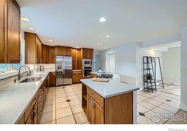 kitchen featuring a kitchen island, sink, light tile patterned floors, stainless steel appliances, and light stone countertops