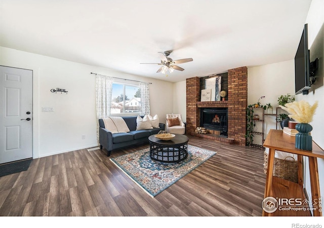 living room featuring ceiling fan, a brick fireplace, and dark hardwood / wood-style flooring