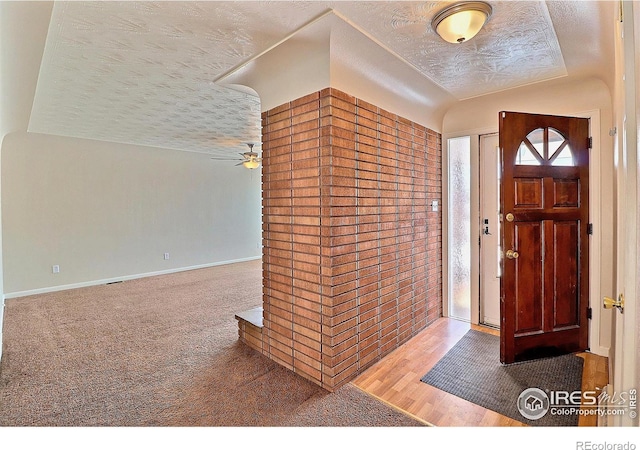 foyer with ceiling fan, a textured ceiling, and carpet flooring