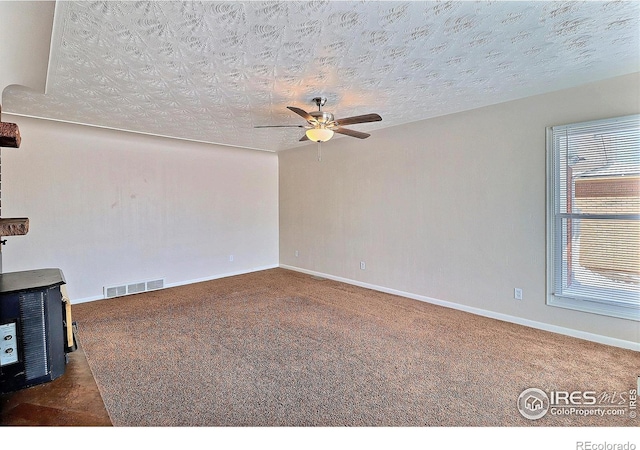 carpeted empty room with ceiling fan and a textured ceiling