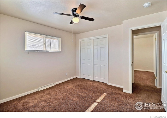 unfurnished bedroom with dark colored carpet, ceiling fan, a baseboard radiator, and a closet