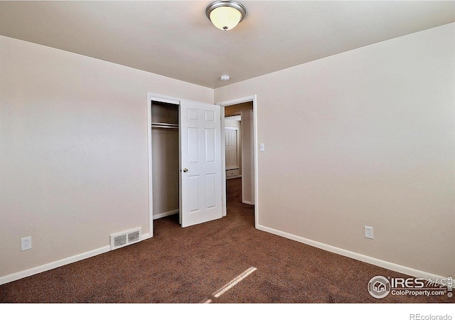 unfurnished bedroom with a closet and dark colored carpet