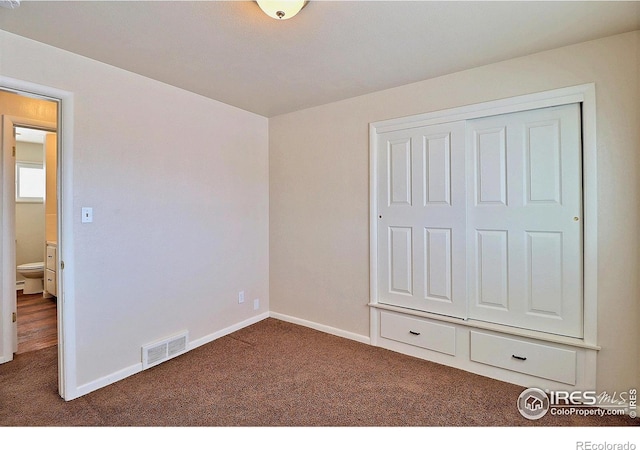 unfurnished bedroom featuring dark carpet and a closet