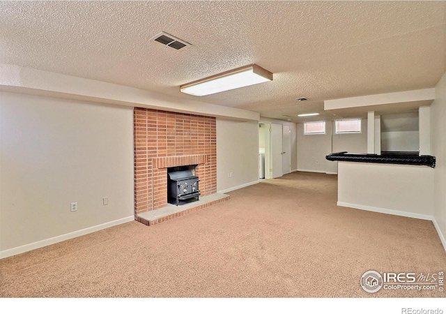 unfurnished living room with a wood stove, carpet, and a textured ceiling