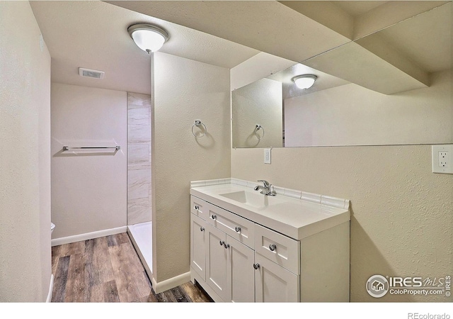 bathroom with vanity, wood-type flooring, and a shower