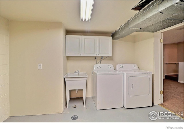 clothes washing area featuring cabinets, sink, and washing machine and dryer