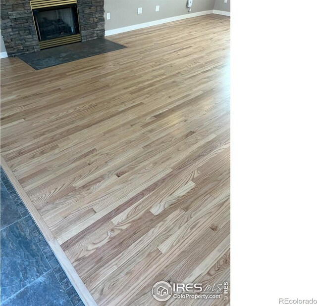 560 S 9th St, Berthoud, CO 80513 - detailed view of baseboards, wood finished floors, and a stone fireplace