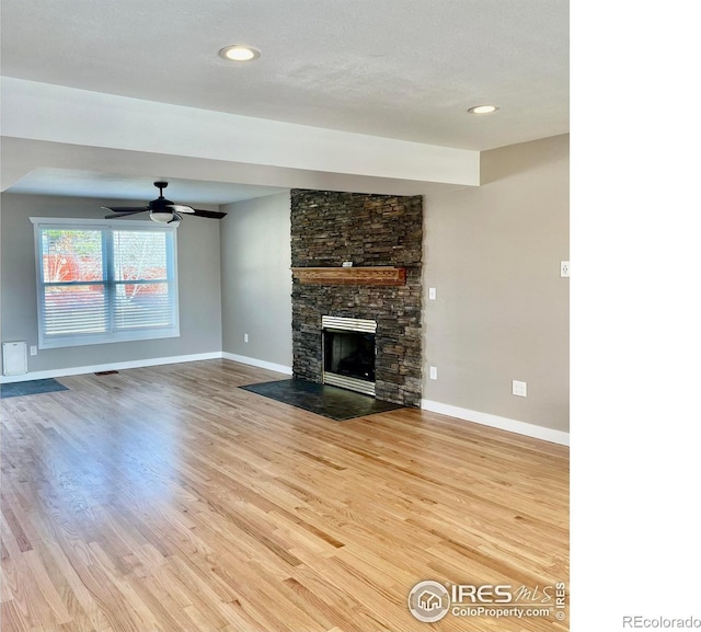 560 S 9th St, Berthoud, CO 80513 - unfurnished living room featuring baseboards, wood finished floors, a stone fireplace, ceiling fan, and recessed lighting