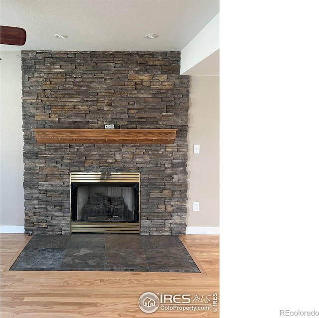 560 S 9th St, Berthoud, CO 80513 - detailed view of wood finished floors, a stone fireplace, and baseboards