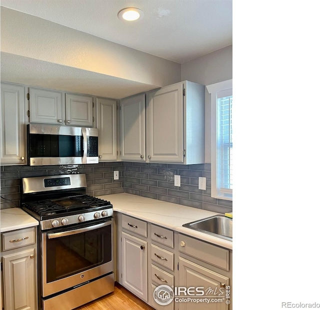560 S 9th St, Berthoud, CO 80513 - kitchen featuring appliances with stainless steel finishes, a sink, light countertops, and decorative backsplash