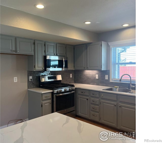 560 S 9th St, Berthoud, CO 80513 - kitchen featuring appliances with stainless steel finishes, gray cabinetry, a sink, backsplash, and recessed lighting