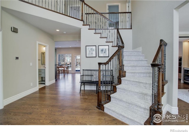 stairs with a high ceiling, baseboards, wood finished floors, and recessed lighting