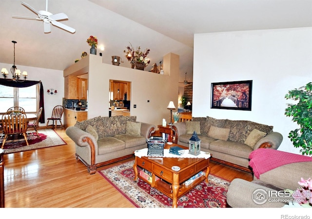 living room featuring hardwood / wood-style flooring, ceiling fan with notable chandelier, and high vaulted ceiling