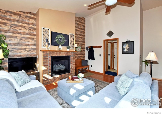 2707 Sedona Hills Dr, Loveland, CO 80537 - living room with ceiling fan, hardwood / wood-style floors, high vaulted ceiling, a brick fireplace, and wood walls