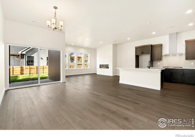 unfurnished living room with dark hardwood / wood-style flooring, sink, and a notable chandelier