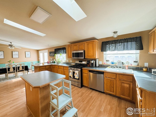 kitchen featuring sink, a center island, appliances with stainless steel finishes, kitchen peninsula, and light hardwood / wood-style floors