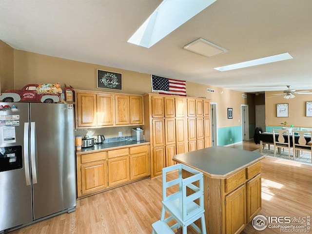 kitchen featuring ceiling fan, a center island, stainless steel fridge, and light hardwood / wood-style floors