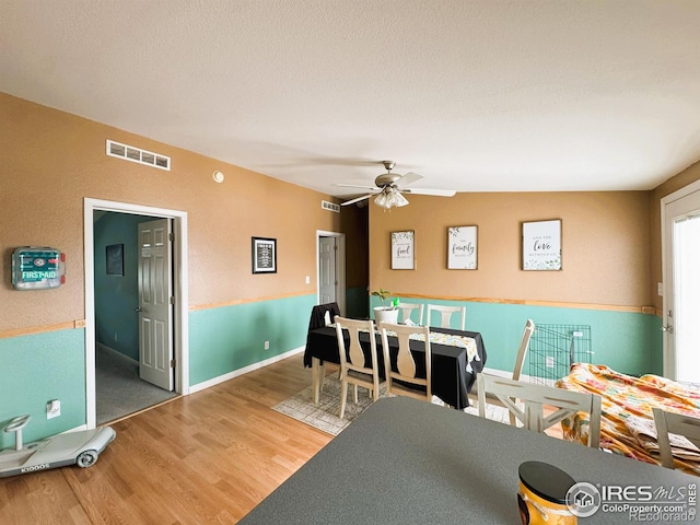 dining space featuring hardwood / wood-style flooring, ceiling fan, and a textured ceiling