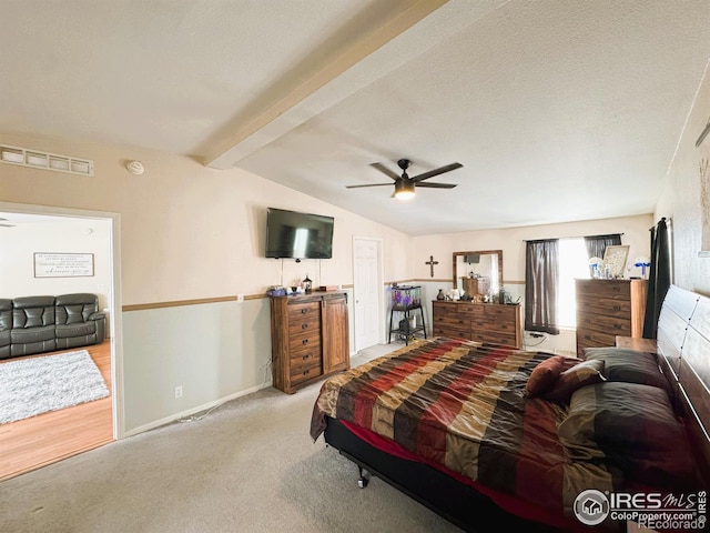 bedroom featuring ceiling fan, a textured ceiling, light carpet, and vaulted ceiling with beams