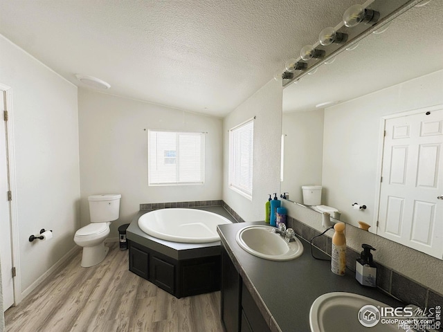 bathroom with a washtub, wood-type flooring, a textured ceiling, vaulted ceiling, and toilet