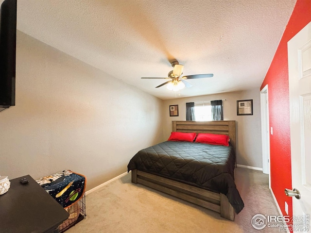 bedroom with ceiling fan, light colored carpet, and a textured ceiling