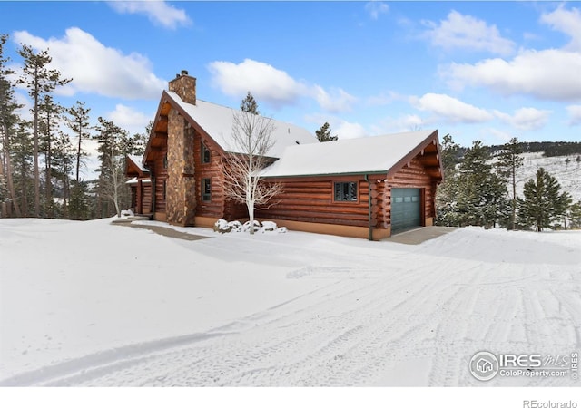 view of front of home with log siding, a chimney, and a garage