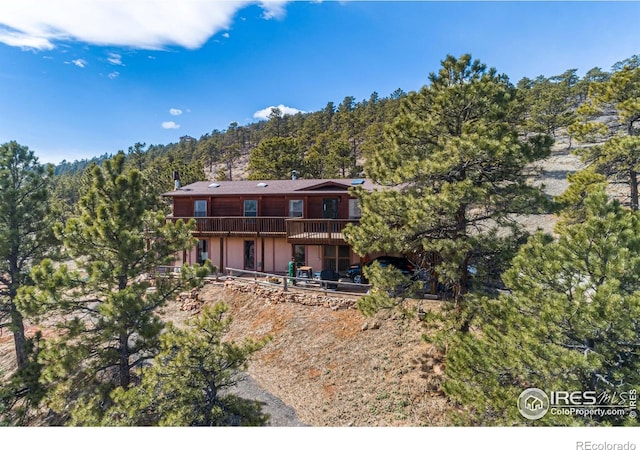 rear view of property featuring a wooded view and a wooden deck