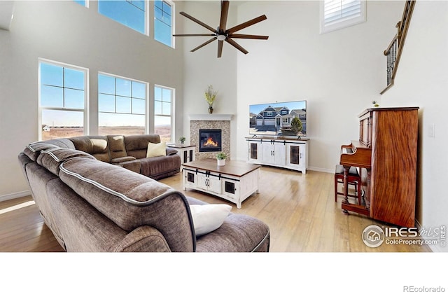 living room with ceiling fan, light hardwood / wood-style floors, and a high ceiling