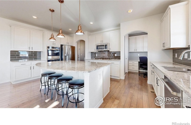 kitchen with sink, white cabinetry, decorative light fixtures, a center island, and appliances with stainless steel finishes