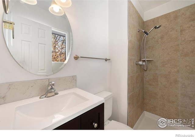 bathroom featuring vanity, toilet, and tiled shower