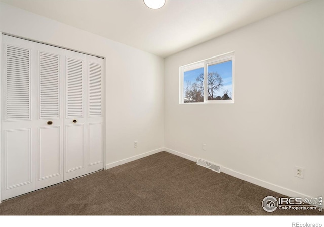 unfurnished bedroom featuring dark carpet and a closet