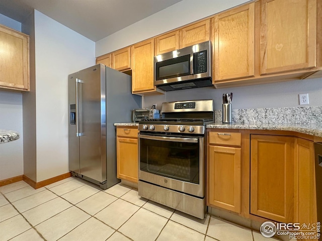 kitchen featuring light tile patterned floors, light stone countertops, and appliances with stainless steel finishes