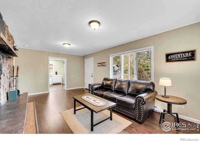 living room with a textured ceiling, dark wood-type flooring, and baseboards