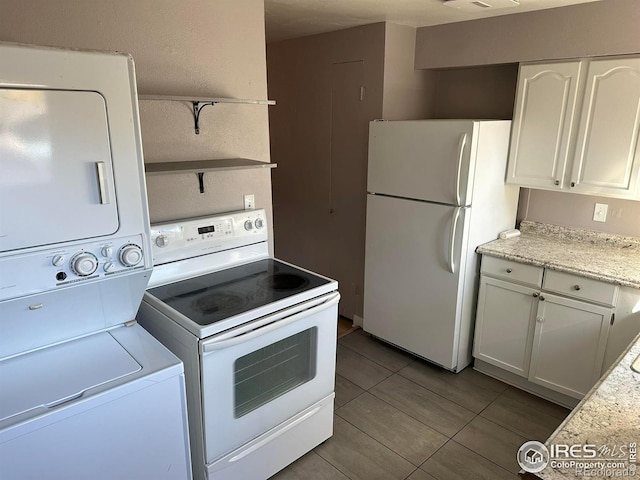 kitchen with stacked washer and dryer, light tile patterned floors, white cabinets, and white appliances