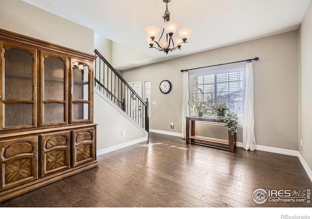 foyer with dark wood-type flooring and a chandelier