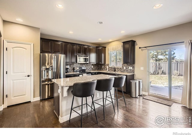 kitchen featuring stainless steel appliances, tasteful backsplash, a center island, and dark hardwood / wood-style flooring