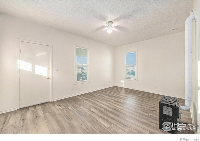 empty room featuring a textured ceiling, light hardwood / wood-style floors, and ceiling fan